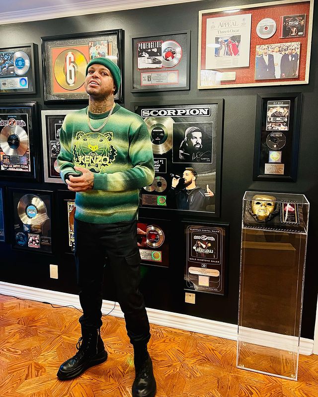 Dj paul standing wearing a green beanie and green sweat shirt with black pants and boots